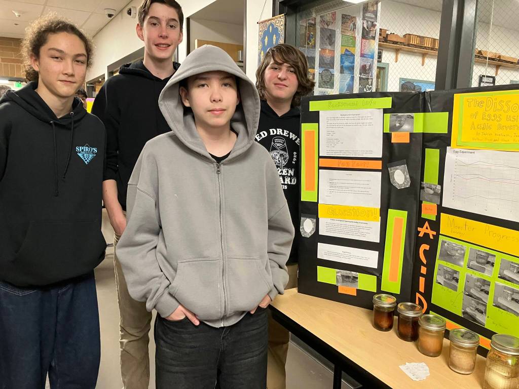(Left to right) Nathan Provo, James Coombs, Jedrick Kozlowski and Hank Roth showed off what they learned from soaking eggs in various liquids, including sodas. (Elizabeth Shepherd photo)