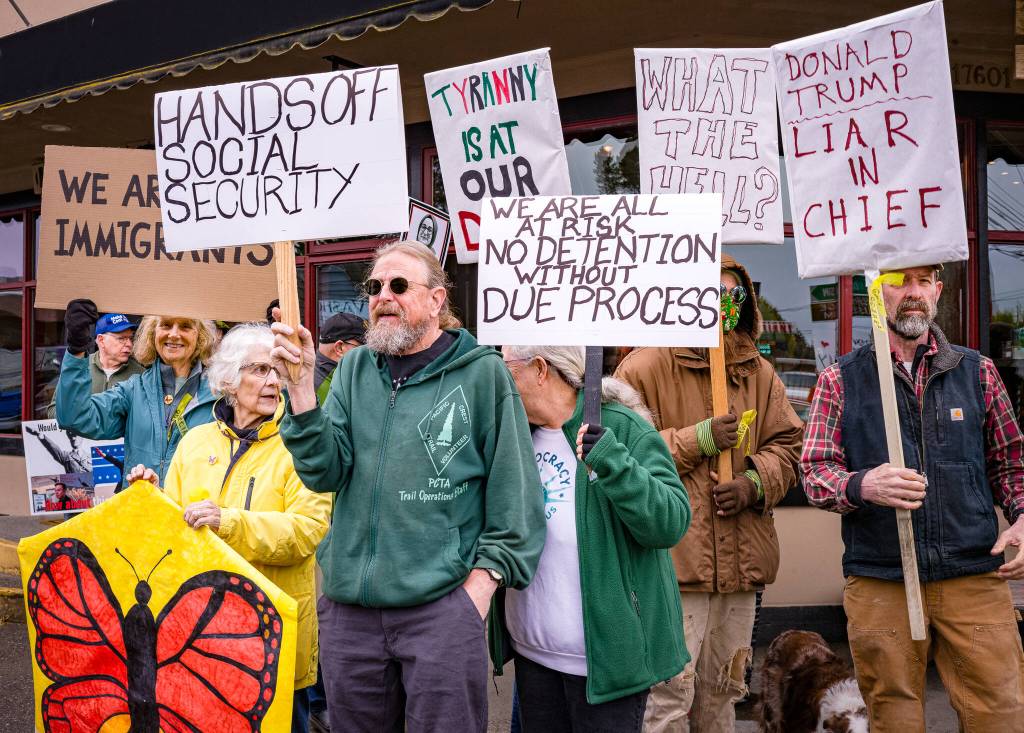 Demonstrators hold signs on Vashon April 19. (Kent Phelan photo)