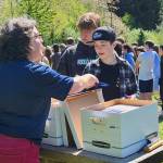 Courtesy photo
English teacher Mandy Davis distributes the book “Minor Poetry” to Liam Bojko and Evan Keller at the seventh grade launch party, while students in the background line up for refreshments.