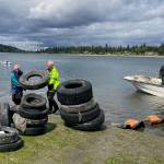 Volunteers George Spano, Kevin Johnson and Captain John Burke unload the boat carrying tires at Jensen Point. (Courtesy photo)