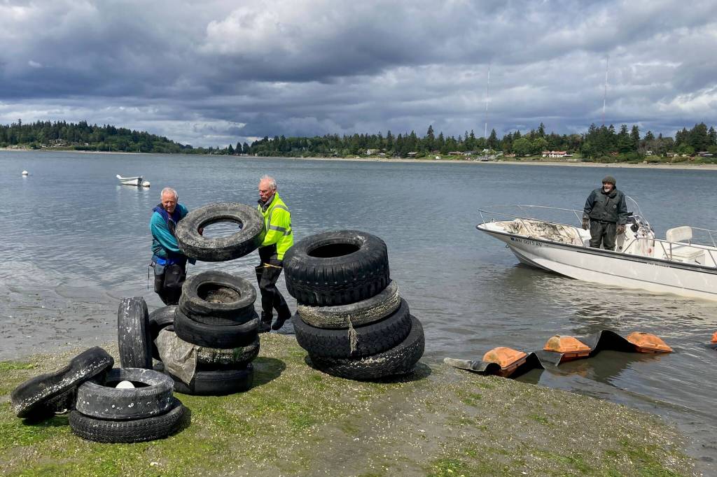 Volunteers George Spano, Kevin Johnson and Captain John Burke unload the boat carrying tires at Jensen Point. (Courtesy photo)