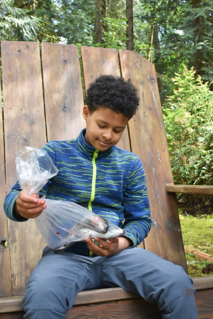 Riley Martinez ponders his fish while sitting on the Sportsmans Clubs huge chair at the pond by the club. (Mari Kanagy photo)