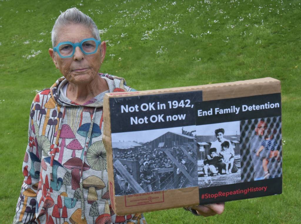 Some attendees at the ceremony held signs drawing comparisons between the 1942 exile and incarceration and current U.S. policy. (Jim Diers photo)