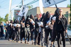 About two dozen demonstrators, organized by the Creative Resistance Action Brigade on Vashon, performed a Theater of Grief for children killed in Gaza during the June 6 First Friday street closure in Vashon Town. Demonstrators, wearing black and carrying white shrouds symbolizing the estimated 15,000 children killed amid Israels strikes in the region, walked solemnly through town to the slow beating of a drum. They stopped periodically to fall to the ground together as a portable speaker played the sound of bomb-dropping aircraft. (Alex Bruell photo)