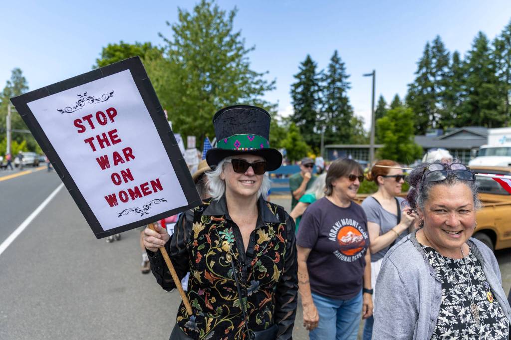 Demonstrators hold signs at the protest on Vashon. (Alex Bruell photo)