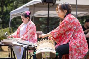 Laryn Young, left, and Hatsune Matsudaira, musicians of the Koto no WA ensemble, played traditional Japanese koto music during the Kizoku Ishiki Obon celebration. The koto is a string instrument, not unlike a harp, which typically features 13 strings plucked by musicians who use three fingerpicks worn on their right hand. (Alex Bruell photo)