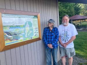 Sue Trevathan and Steve Hunter stand next to a newly designed sign at Dockton Park urging action to protect Quartermaster Harbor. (Leslie Brown Photo)