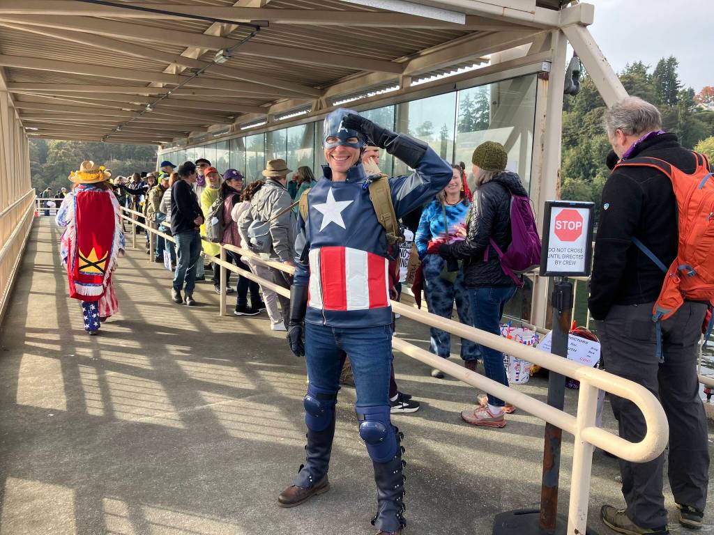 A protester dressed as Captain America waits at the Vashon Water Taxi dock Saturday as islanders line up to travel to Seattle for the demonstration. (Elizabeth Shepherd Photo)