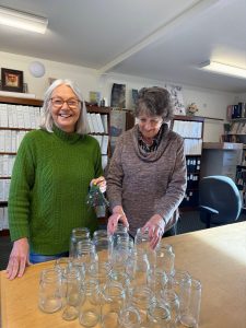 Courtesy Photo
Vashon Heritage Museum volunteers, Susan Martin and Jenny Lewis, with supplies for the upcoming family day. Children will have the opportunity to decorate a glass jar with tissue paper for a colorful lantern. Susan is holding a woven ornament, another craft opportunity for families.
