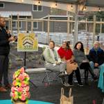 Chris Lovings, community engagement specialist at the Washington State Department of Commerce, speaks to the crowd at Island Center Homes in Dec. 2024. Hilary Emmer sits on the far right. (John Decker Photo)
