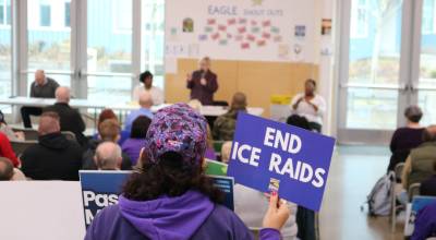 An attendee at the Feb. 21 town hall in Federal Way holds a sign calling for an end to ICE raids. Courtesy photo