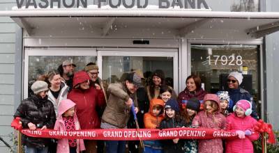 Vashon Food Bank Executive Director Emily Scott cuts the grand opening ribbon on Friday, March 13, surrounded by food bank staff, Chautauqua Elementary School students, Councilmember Teresa Mosqueda and Pastor Patricia Longstroth. (Scarlet Hansen Photo)