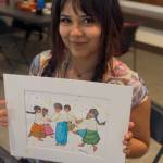 Colwells granddaughter, Kamila, holds up a painting by Colwell at Día del Niño.