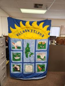 Photo courtesy of the Heritage Museum
A Bicentennial quilt stitched by fifth graders at Vashon Elementary School in 1976 is preserved in the Vashon History Museum archives. The quilts embroidered panels celebrate both American history and life on Vashon. Each panel is signed by the student who created it.