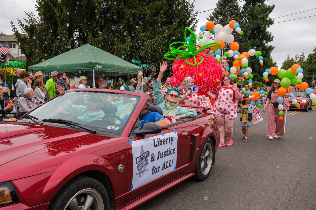 Kent Phelan Photo
Indivisible Vashon members wave from a convertible as a giant strawberry and bubbles fill the parade route.