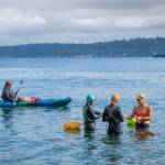 Mary Singer, in the bright orange and purple suit, gathers with fellow open-water swimmers before a practice swim in Puget Sound. (Terry Donnelly Photo)