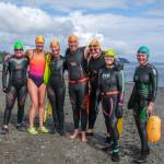 Mary Singer, second from left in the bright suit, stands with fellow Vashon open-water swimmers before a practice swim in Puget Sound. (Terry Donnelly Photo)
